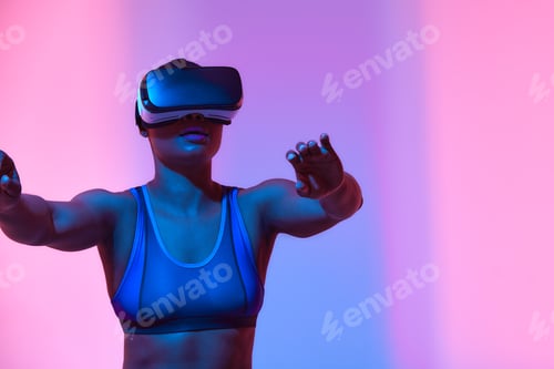 Preview: Amazed young woman touching the air during the VR experience. Horizontal studio shot.
