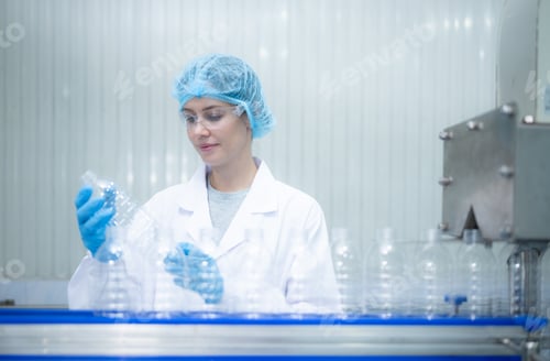 Preview: Female quality control worker inspecting water bottle on production line in drinking water factory