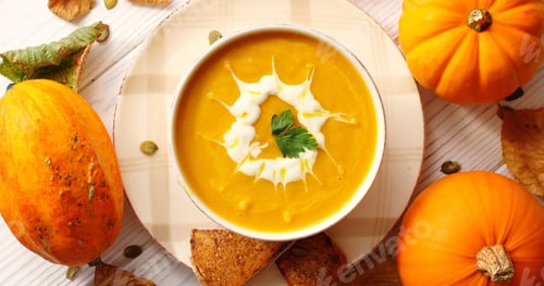 Preview: Creamy pumpkin soup in bowl with herb