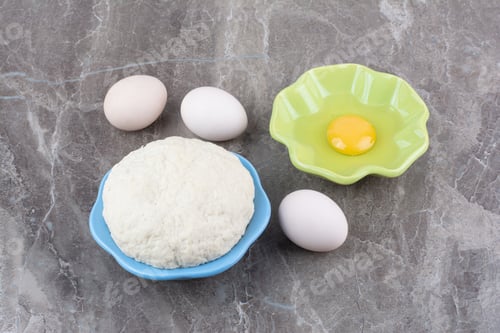 Preview: Dough on wooden board with green plate of raw egg
