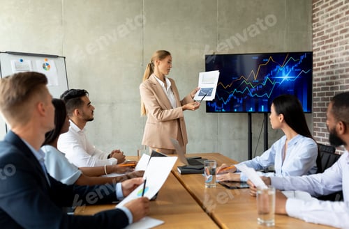 Preview: Corporate Meeting. Young Businesswoman Giving Speech During Conference With Coworkers In Office