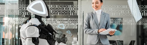 Preview: panoramic shot of smiling asian businesswoman holding digital tablet while looking at robot