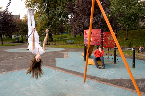 Preview: Teenage girl on swing in playground, upside down