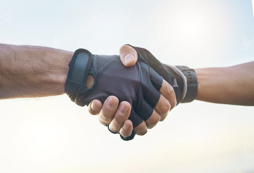 Preview: Teamwork, cycling and sports men shaking hands outdoor together against a sky background with flare