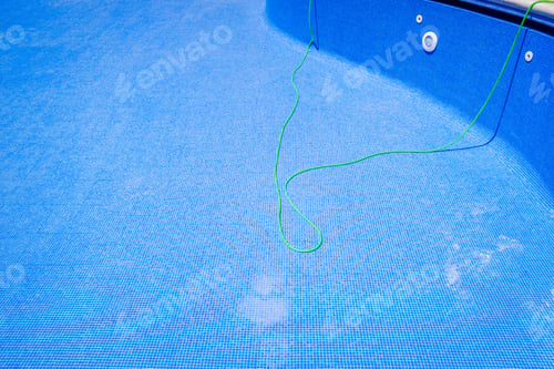 Preview: A hose to clean an empty swimming pool in summer.