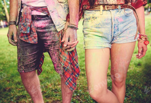 Preview: Waist down view of young couple covered in coloured chalk powder at festival