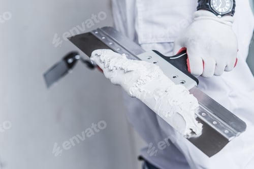 Preview: Contractor Holding Putty Knife with Filler in Hand