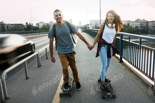 Preview: Young attractive couple riding skateboards and having fun