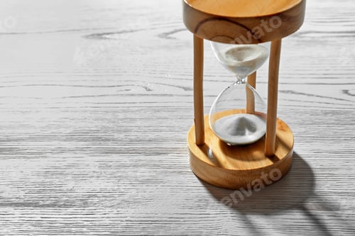 Preview: Hourglass with flowing sand on light wooden background. Time management