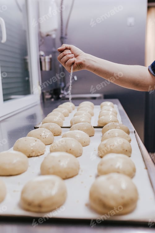 Preview: woman in bakery preparing sweets adding sugar.
