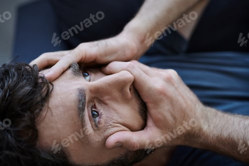 Preview: stressed desperate man with beard in casual attire lying with hands on face during mental breakdown