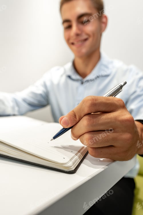 Preview: Young businessman making notes at tabletop in office