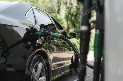 Preview: Selective focus of fueling nozzle in gas tank of auto and woman paying with credit card near worker