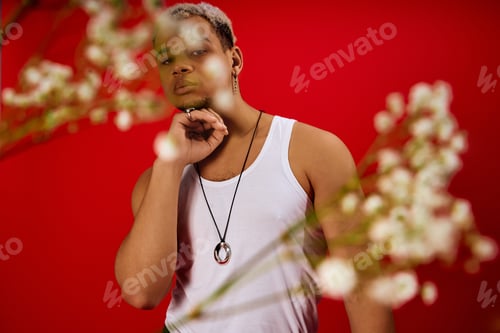Preview: Young stylish man in red studio showcasing trendy fashion with confidence and flair