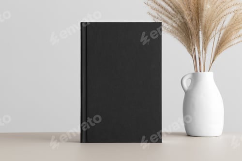 Preview: Black book mockup with a reed pampas decoration on the beige table.
