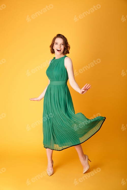 Preview: young happy woman in green dress isolated on orange