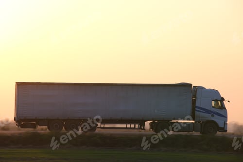 Preview: Semi-truck with cargo trailer driving on highway hauling goods in evening.