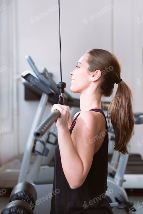 Preview: Young woman doing exercises on a machine at the gym