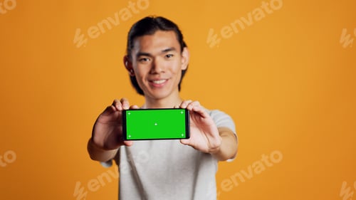 Preview: Male model holding horizontal greenscreen mobile phone