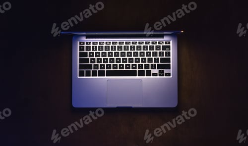 Preview: Top view of a laptop on a dark table, glowing screen.