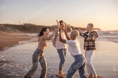 Preview: Diverse friends group celebrating success on beach at sunset