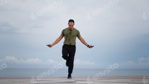 Preview: Man warm up jump rope against the ocean during cloudy day
