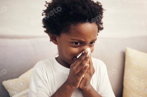 Preview: Cold and flu season. Sick african american boy with afro blowing nose into tissue. Child suffering