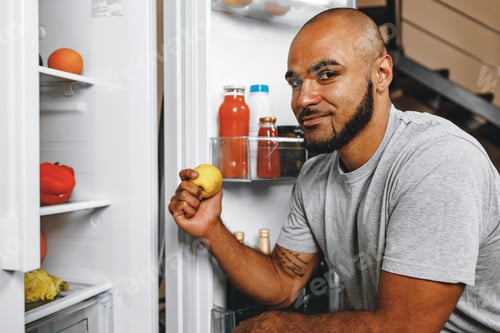 Preview: African american man taking food from a fridge in his house
