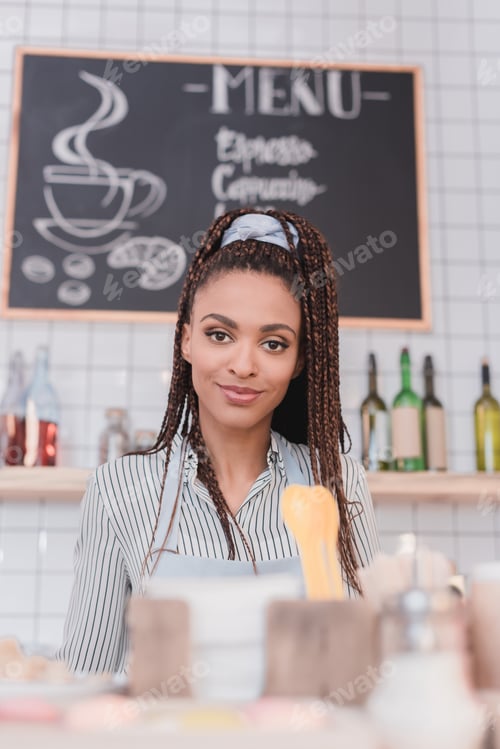Preview: Young african american barista standing behind the counter at coffee shop