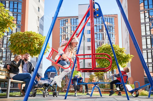 Preview: Happy family - father, mother and children having fun together on playground.