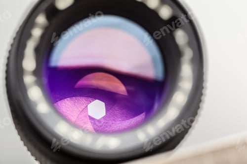 Preview: Close-up view of a camera lens showing colorful reflections and aperture blades