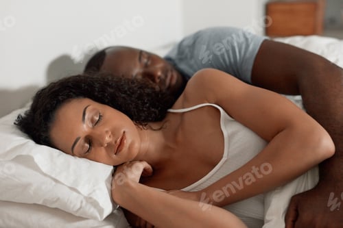Preview: Shot of a tired young couple sleeping comfortably together in their bed at home in the morning