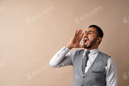 Preview: Young arab man shouting and screaming loud against beige background