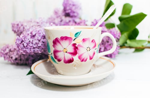 Preview: Cup of tea and flowers of a lilac on a white wooden background. Copy space