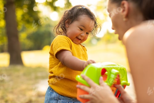Preview: Asian Mommy Giving Her Baby Daughter Plastic Toy Playing Outdoors