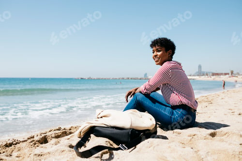 Preview: Woman sitting on the beach enjoying the sun after work
