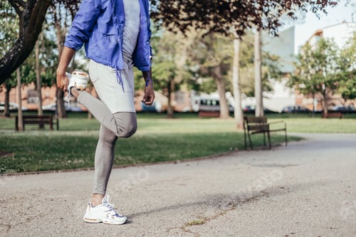 Preview: unrecognizable black ethnicity man stretching quadriceps in park