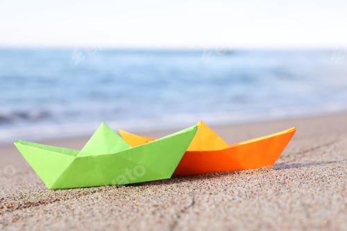 Preview: Bright color paper boats on sandy beach near sea