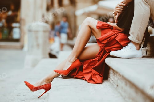 Preview: Female wearing a red high-heeled shoe sitting on a step with her boyfriend