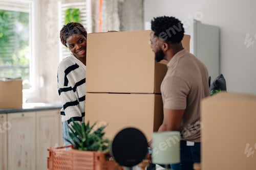 Preview: Happy couple moving into new home carrying boxes