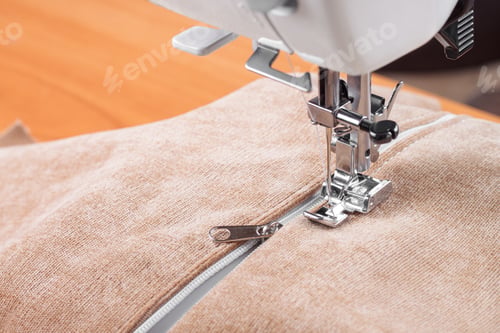 Preview: Modern sewing machine special presser foot with beige fabric and zipper, closeup