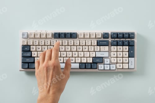 Preview: Woman hand typing on keyboard on blue background. View from above. Flat lay.