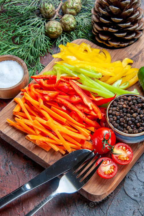 Preview: bottom half view colorful cut peppers black pepper tomatoes on cutting board salt fork and knife