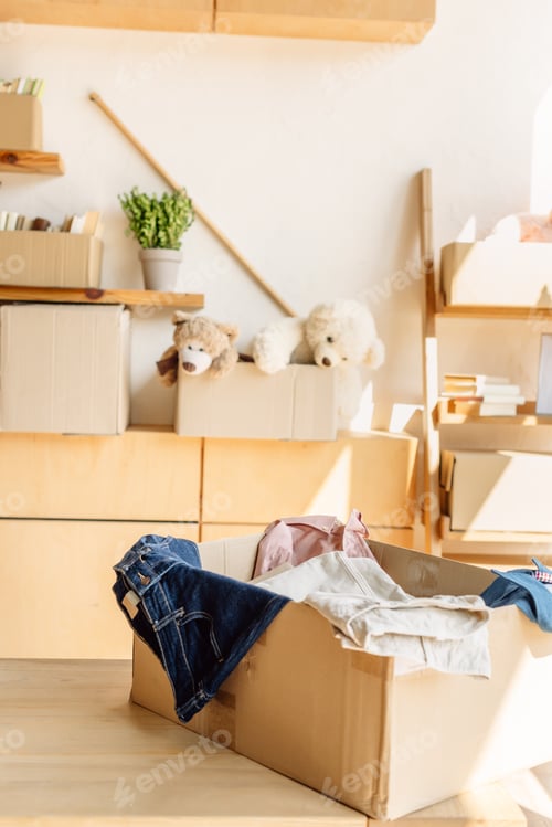 Preview: wooden cabinets and cardboard boxes with clothes, books and toys in charity center