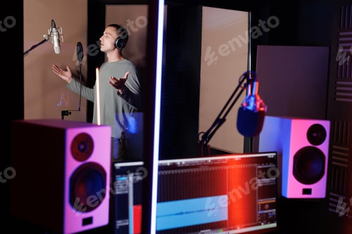 Preview: Young musicican singing into a microphone while laying down tracks in a music studio.