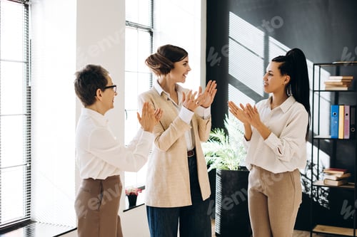 Preview: Enthusiastic businesswomen clapping hands celebrating success in office