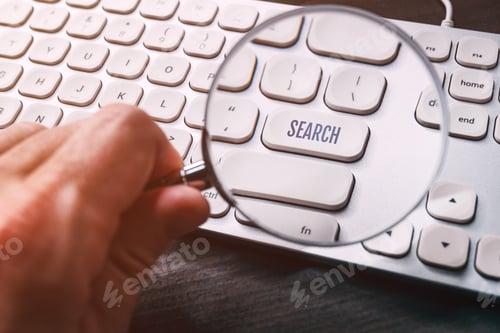 Preview: Search button key on computer keyboard seen through magnifying glass loupe