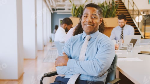 Preview: Portrait Of Mature Businessman In Modern Office With Colleagues Meeting Around Table In Background