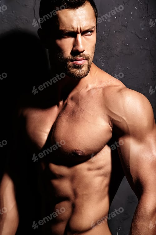 Preview: Portrait of young strong man with perfect sportive body posing in studio