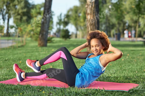 Preview: Adorable little girl in sportswear doing exercise in park